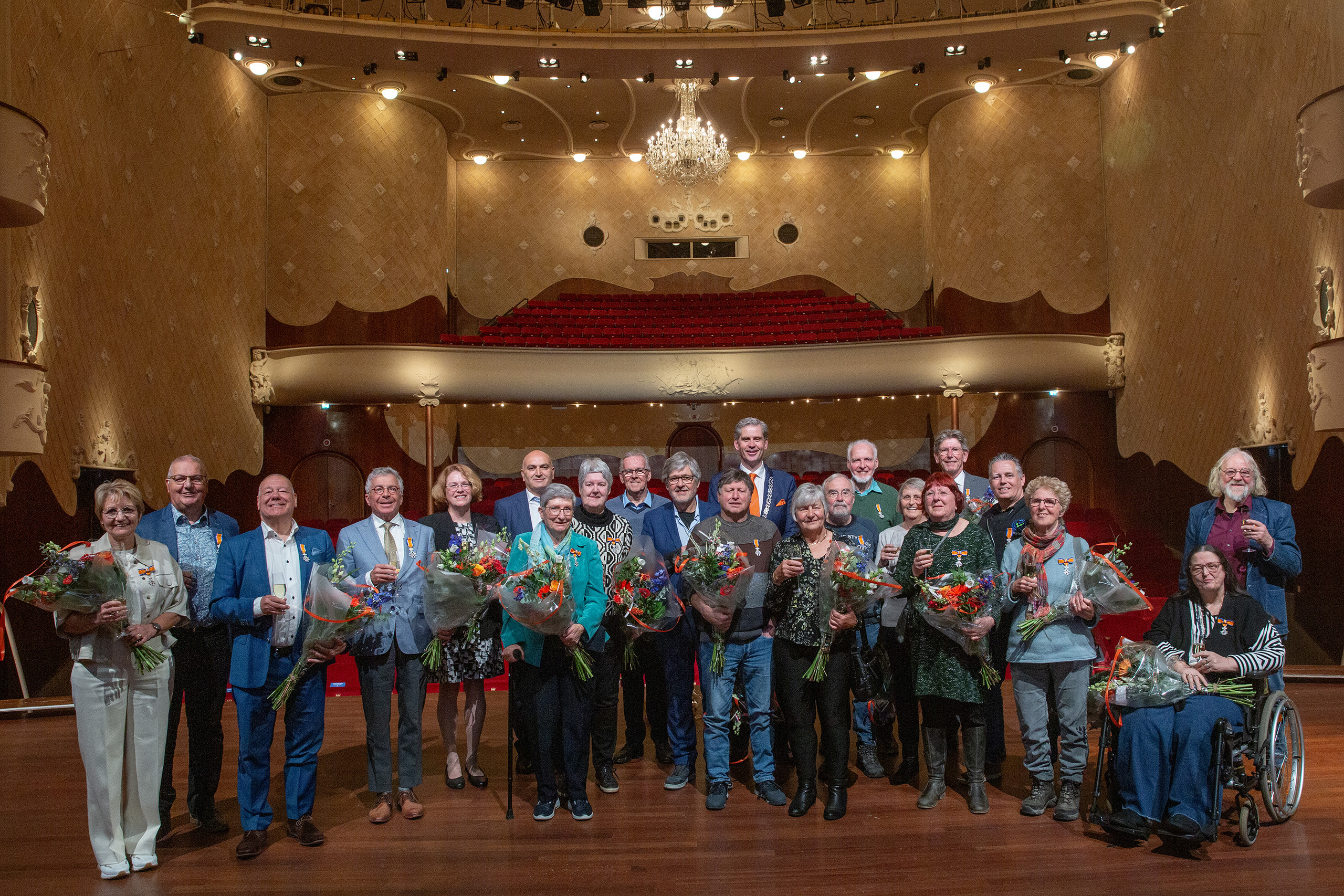 De 21 Dordtenaren die een Koninklijke onderscheiding hebben gekregen op de foto met een bos bloemen. 
