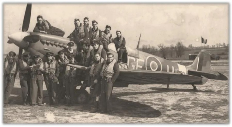 Foto uit 1944 van het Spitfire LF IXe jachtvliegtuig. Het vliegtuig is omringd door een groep jonge piloten van de Britse Royal Air Force.